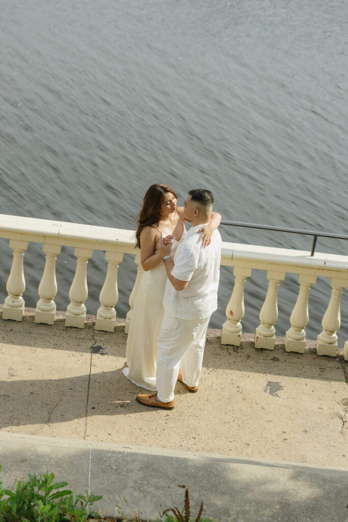 Elegant-couple-embracing-during-their-engagement-session-at-Fairmount-Water-Works-in-Philadelphia-with-the-Schuylkill-River-and-historic-architecture-in-the-background